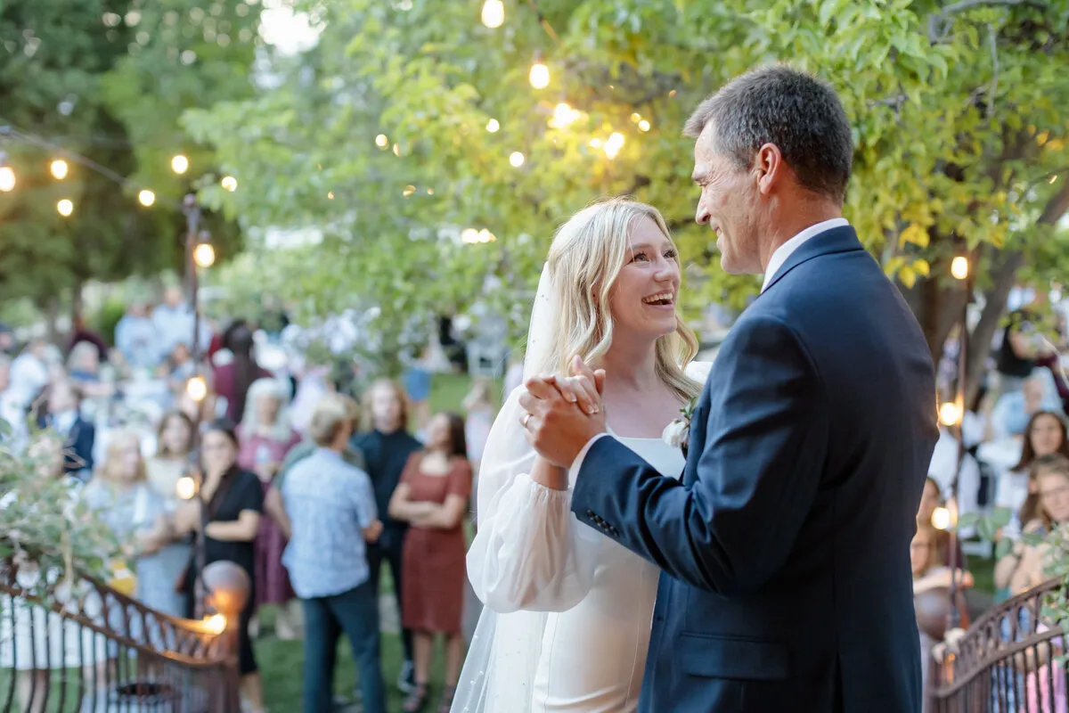 Bride and her father dance during a garden reception