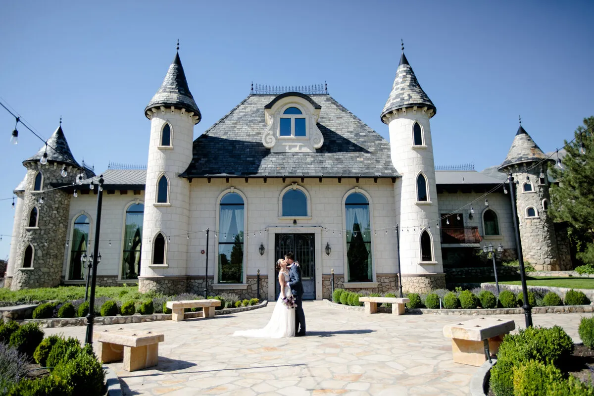 A bride and groom kiss in front of the castle