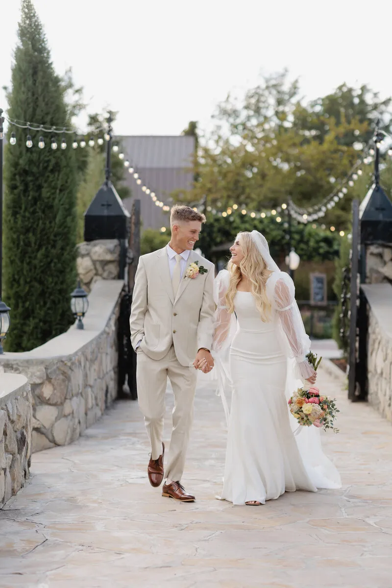 Bride and Groom hold hands while walking toward the castle